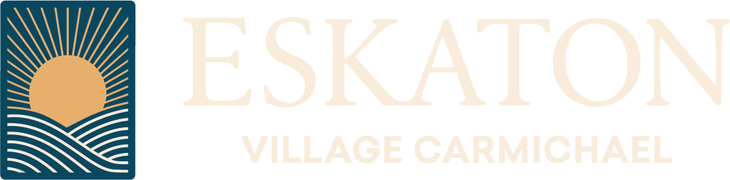 Logo for Eskaton Village Carmichael featuring a stylized sun rising over wavy lines, with the text ESKATON VILLAGE CARMICHAEL in large, light-colored font.